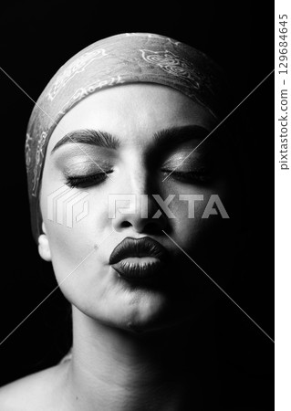 Portrait of a young woman sending kiss isolated over black background 129684645