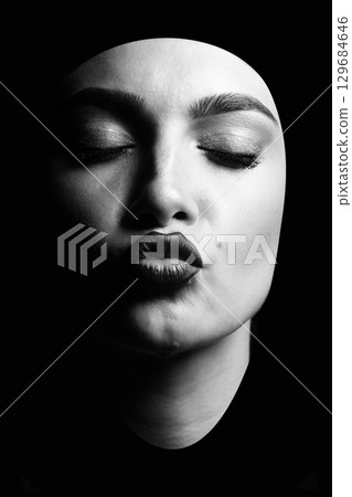 Portrait of a young woman sending kiss isolated over black background 129684646
