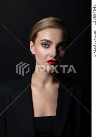 Beautiful woman with classic hairstyle and black suit close-up studio portrait 129684648