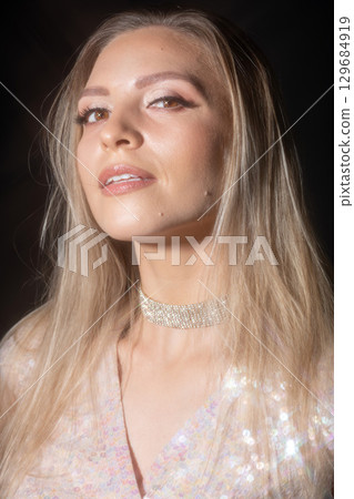 Beautiful blonde woman with shiny blouse studio portrait 129684919