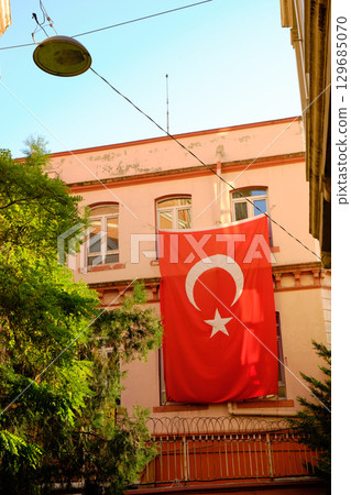 A Turkish flag hangs on a building facade in a sunny urban setting in Istanbul, Turkey 129685070