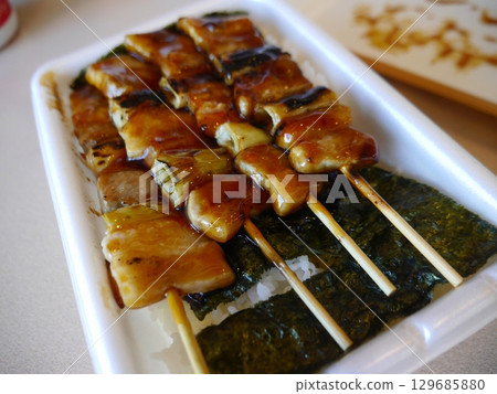 A bento box topped with yakitori 129685880