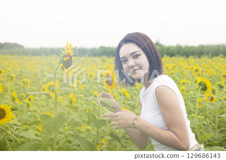 A woman walking in a sunflower field A woman walking in a sunflower field 129686143