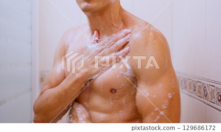 Man washing his chest with soap in the shower Man washing his chest with soap in the shower 129686172