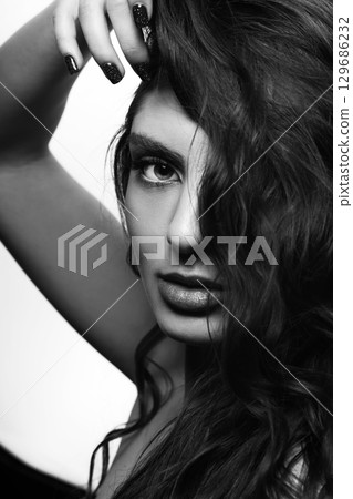 Brunette woman with long wavy hair sensual studio portrait Brunette woman with long wavy hair sensual studio portrait 129686232