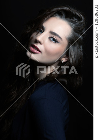 Brunette woman with long wavy hair sensual studio portrait Brunette woman with long wavy hair sensual studio portrait 129686233