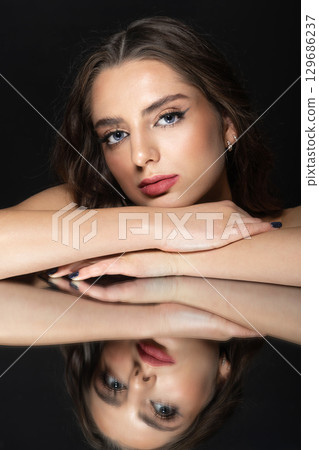 Portrait of beautiful woman with wavy hair and makeup face reflection in mirror Portrait of beautiful woman with wavy hair and makeup face reflection in mirror 129686237