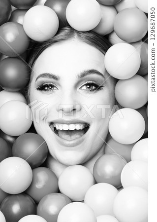 Beautiful woman close-up studio black and white portrait in balls background Beautiful woman close-up studio black and white portrait in balls background 129687050