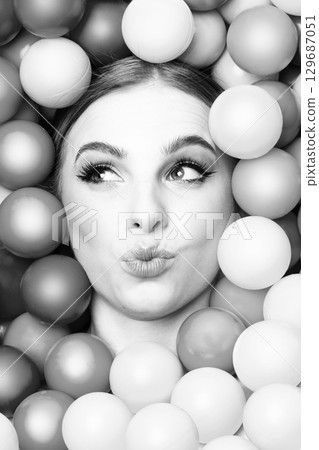 Beautiful woman close-up studio black and white portrait in balls background Beautiful woman close-up studio black and white portrait in balls background 129687051