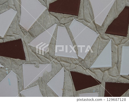 mosaic abstraction of broken triangular tiles of white and burgundy color in the texture of a cement wall, simple decoration of an architectural object with a mosaic of ceramic tiles 129687128