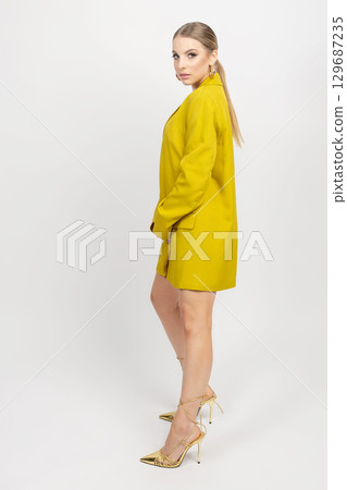 Woman studio portrait with yellow jacket and naked legs 129687235
