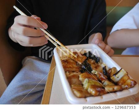 Man eating yakitori bento (no face) 129687353
