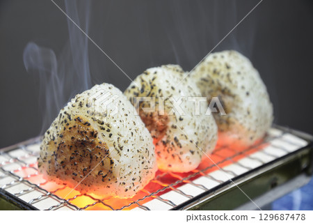 Grilling rice balls on a charcoal grill with smoke rising Grilling rice balls on a charcoal grill with smoke rising 129687478