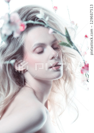 Beautiful woman with big wavy hair and flowers studio portrait 129687513