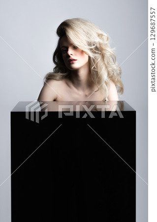 Beautiful woman with big wavy hair and black cube studio portrait Beautiful woman with big wavy hair and black cube studio portrait 129687557