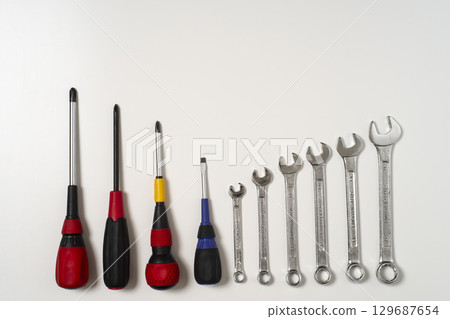 Screwdrivers and combination wrenches lined up on a white background Screwdrivers and combination wrenches lined up on a white background 129687654