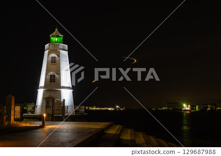 Illuminated lighthouse at night 129687988