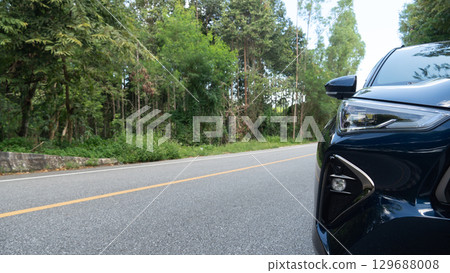Traveling of dark blue car on asphalt road. Front of car driving on the road with nature of trees forest. 129688008