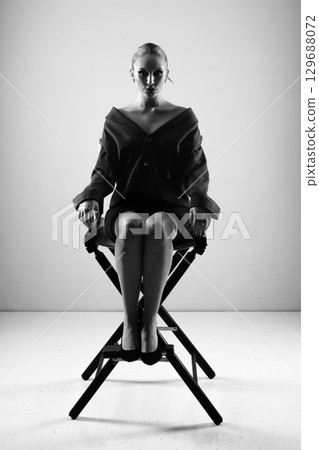 Beautiful woman black and white portrait with jacket and mini shirt sitting in high chair Beautiful woman black and white portrait with jacket and mini shirt sitting in high chair 129688072