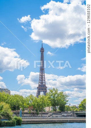 The Eiffel Tower seen from the Seine: a view of Paris against the blue sky and greenery The Eiffel Tower seen from the Seine: a view of Paris against the blue sky and greenery 129688102
