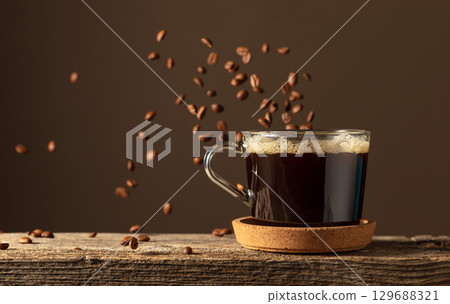 Black coffee in glass cup on an old wooden board. Black coffee in glass cup on an old wooden board. 129688321