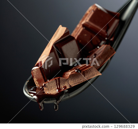 Melting pieces of bitter chocolate on a black background. Melting pieces of bitter chocolate on a black background. 129688329