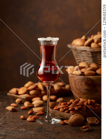 Italian liqueur Amaretto with almonds nuts on a brown background. 129688359
