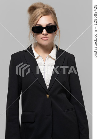 Beautiful woman with black suit and sunglasses studio portrait portrait 129688429