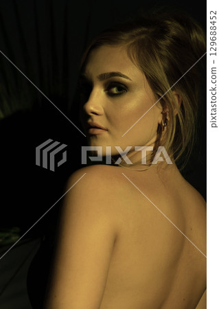 Beautiful woman with naked back and palm leaf studio portrait 129688452