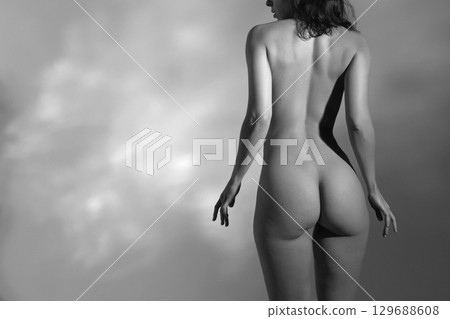 Woman with beautiful naked body studio portrait illuminated with light 129688608