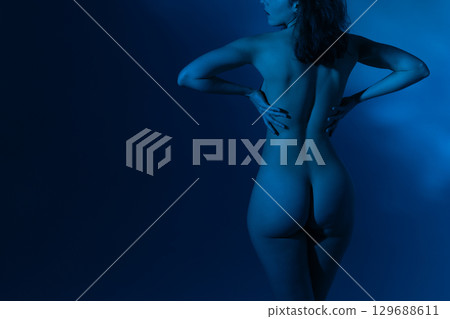 Woman with beautiful naked body studio portrait illuminated with blue light 129688611