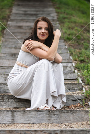 Serene Woman Sitting on Wooden Path in Nature 129688827