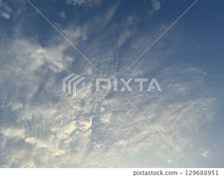 The sky with clouds illuminated by the setting sun 129688951