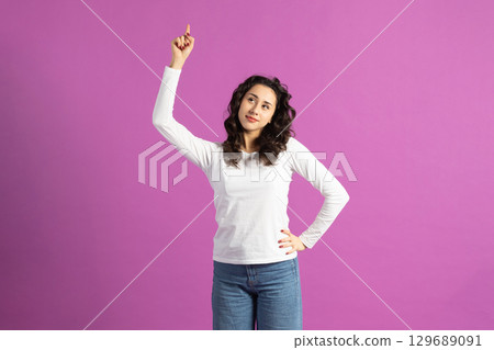 Beautiful woman pointing finger up and looking with suspicious facial expression 129689091