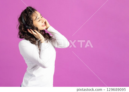 Woman with headphones on pink background 129689095