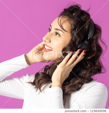 Woman with headphones on pink background 129689096