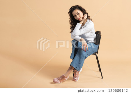 Studio portrait of woman sitting on chair 129689142
