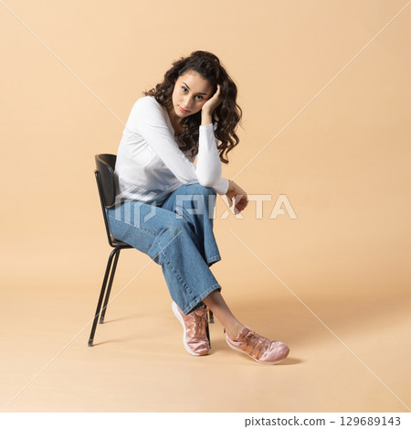 Studio portrait of woman sitting on chair 129689143