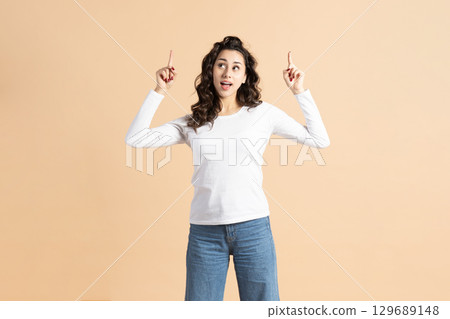 Amazed young woman pointing fingers to air 129689148