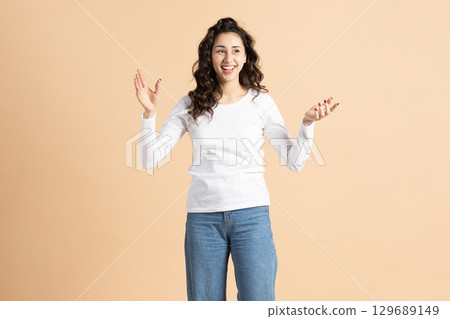Happy woman studio portrait on beige background Happy woman studio portrait on beige background 129689149