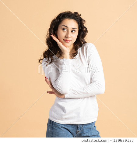 Thoughtful woman portrait on beige background Thoughtful woman portrait on beige background 129689153