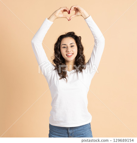 Beautiful woman showing fingers heart sign Beautiful woman showing fingers heart sign 129689154