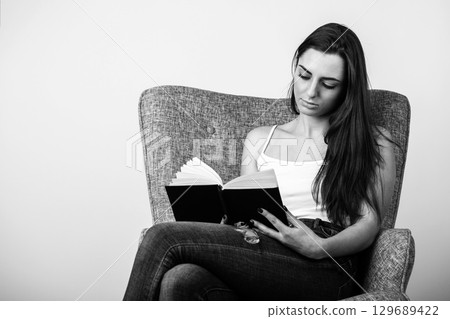 Black and white studio portrait of beautiful woman reading book 129689422