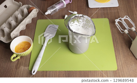 Whipped egg white in glass. Making dessert in the kitchen at home. Quality products. 129689548