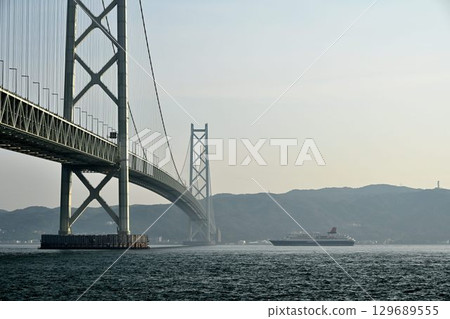 A distant view of a cruise ship passing through the Akashi Kaikyo Bridge from the Bridge Science Museum in Maiko Park 129689555