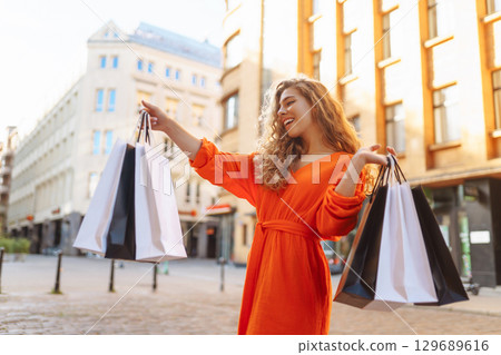 Young woman with shopping bags near mall. Purchases, shopping, lifestyle, sale concept. 129689616