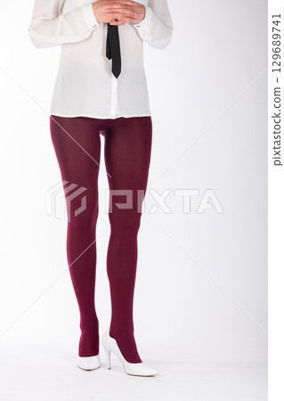 Woman legs with burgundy tights and white high heel shoes 129689741