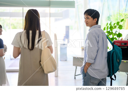 A group of male and female students walking inside the school building 129689785