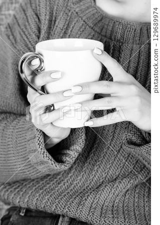 Woman with sweater holding cup of hot drink 129689974