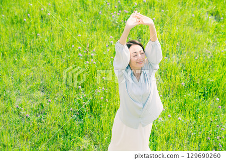 Young woman stretching in the grassland Lifestyle image Young woman stretching in the grassland Lifestyle image 129690260